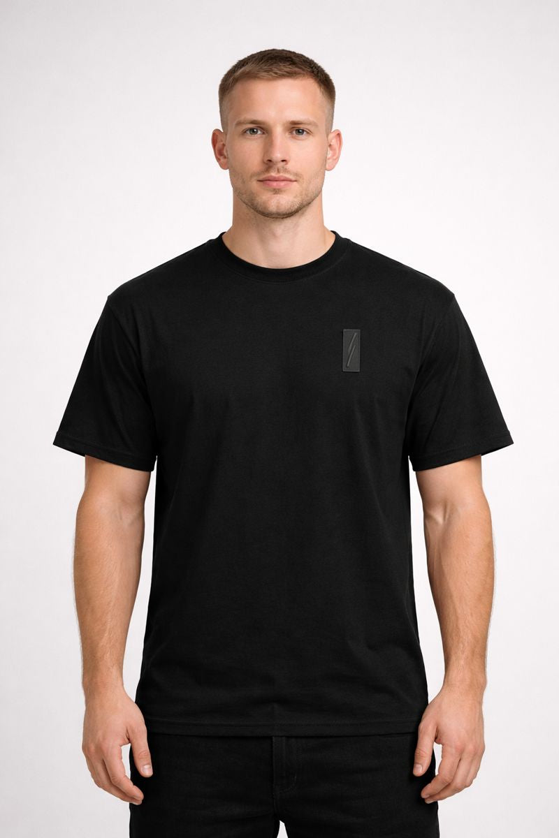 Minimalist crewneck tee with tonal chest badge and gold back-neck crest. Soft, breathable comfort in Black or White—an elevated everyday essential.