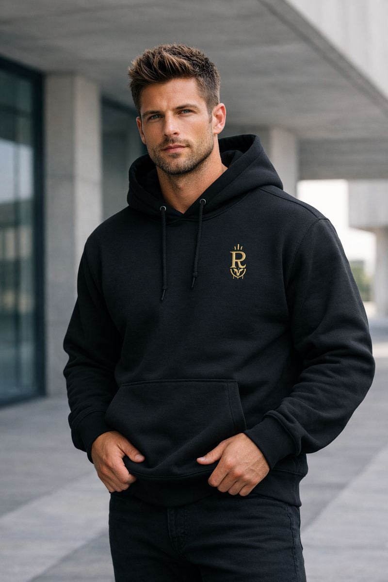 Man wearing a black hoodie with a logo, standing outdoors.