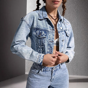 Person wearing a light blue denim jacket and jeans against a gray background