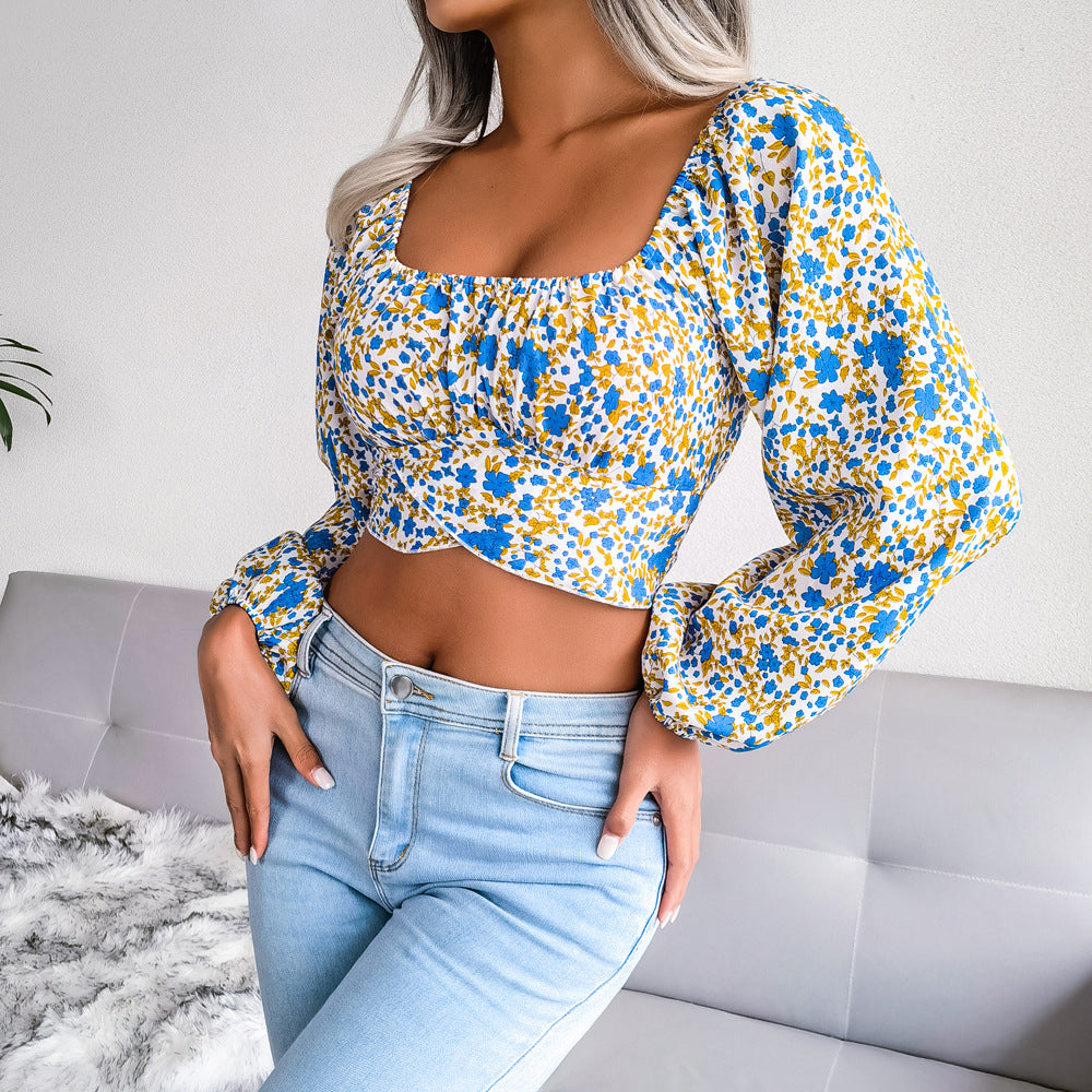 Woman wearing a floral top and jeans sitting on a couch.