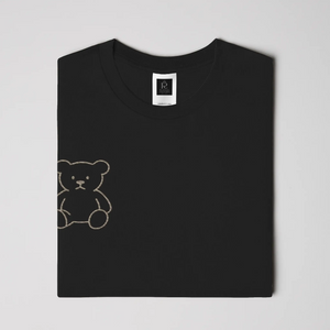 Black streetwear t-shirt featuring small gold crest logo on upper back, minimalist premium design