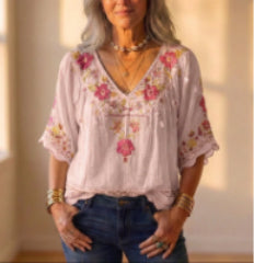 Woman wearing a floral embroidered top and denim shorts indoors.