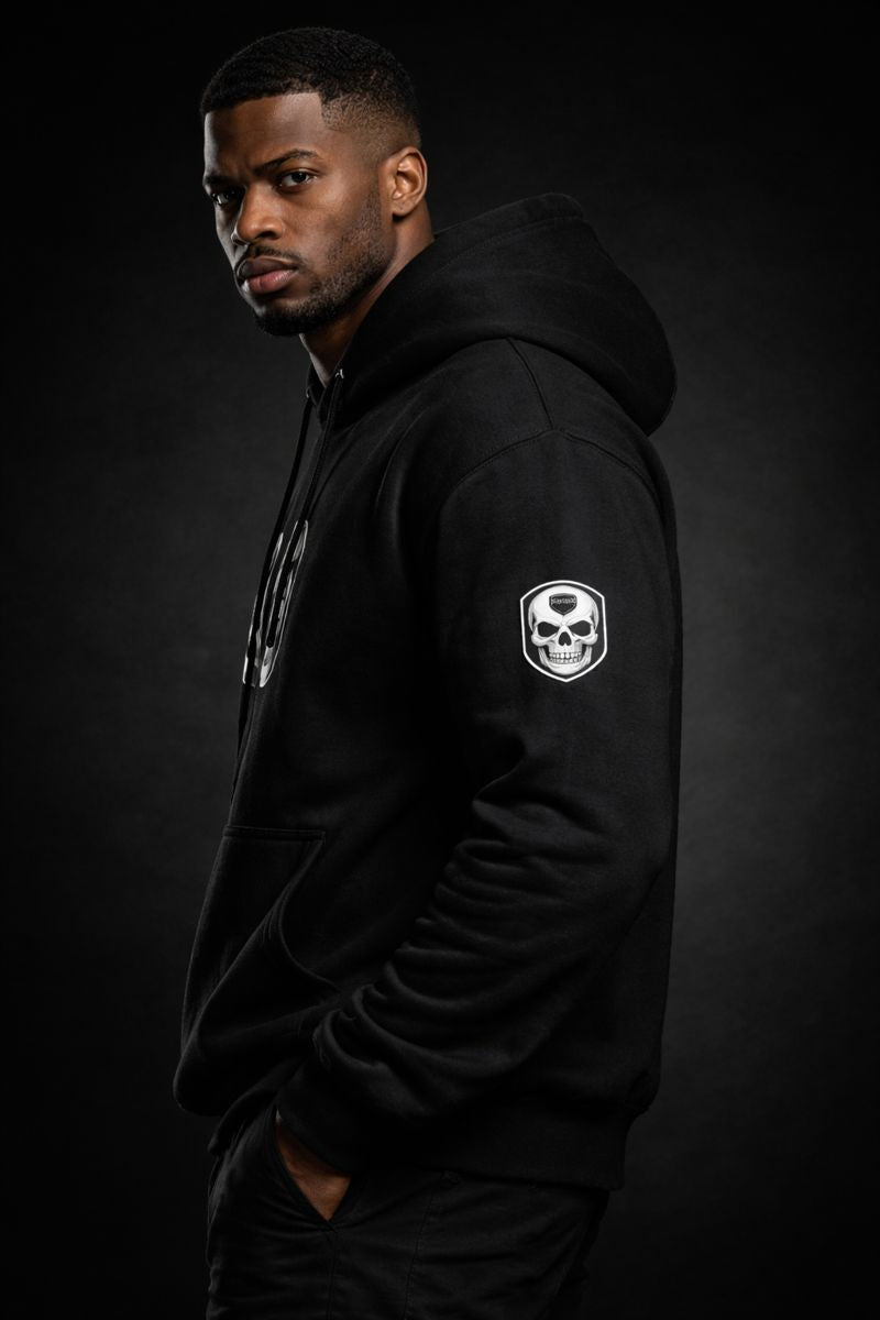 Side profile of SENTINEL HOODIE showing sleeve skull logo on strong Black male model
