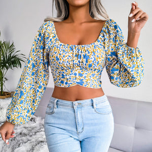 Woman wearing a floral blouse and light blue jeans indoors.