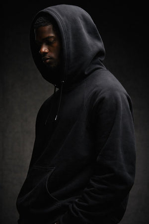 Black premium streetwear hoodie with gold chest crest and symbolic back graphic worn by a Black male model in a minimalist luxury photoshoot.